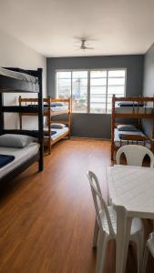 a room with three bunk beds and a table at Hostel 116 Centro Canoas in Canoas