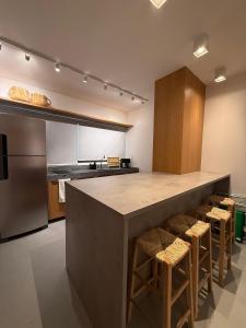 a kitchen with a large counter with stools at Beira Mar Japaratinga Brisa in Japaratinga