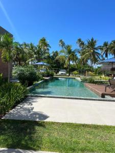 a swimming pool in a resort with palm trees at Beira Mar Japaratinga Brisa in Japaratinga