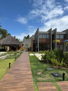 a wooden walkway leading to a building with a resort at Beira Mar Japaratinga Brisa in Japaratinga