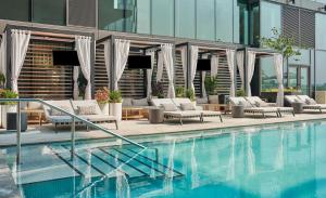 a swimming pool with lounge chairs next to a building at Pendry Washington DC - The Wharf in Washington, D.C.