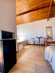 ein Wohnzimmer mit schwarzem Kühlschrank und Holzdecke in der Unterkunft Chalés Nascer da Lua in Monte Verde
