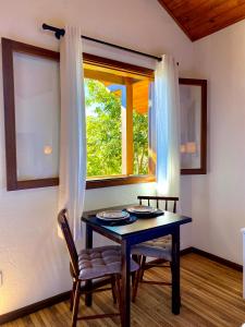 ein Tisch und ein Stuhl in einem Zimmer mit Fenster in der Unterkunft Chalés Nascer da Lua in Monte Verde