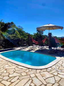 ein Schwimmbecken mit Stühlen und einem Sonnenschirm in der Unterkunft Chalés Nascer da Lua in Monte Verde
