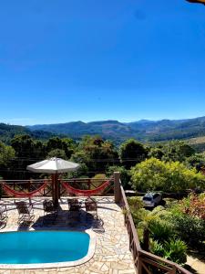 eine Terrasse mit Pool, Stühlen und Sonnenschirm in der Unterkunft Chalés Nascer da Lua in Monte Verde