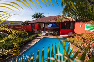 a villa with a swimming pool in front of a house at Sinuca, churrasqueira e fogueira a 300 metros do mar in Itanhaém