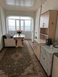 a kitchen with a table and a living room at Грин сити in Balykchy