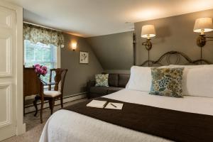 a bedroom with a bed and a chair and a desk at Inn at Pleasant Lake in New London