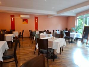 a dining room with tables and chairs with white table cloth at Pensiune Safrane in Băile Herculane