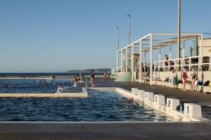 a group of people in the water near a pier at The Calm in Newcastle +4 photos