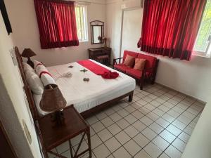 a bedroom with a bed and a red chair at DEPARTAMENTOS LALO in Zihuatanejo +29 photos