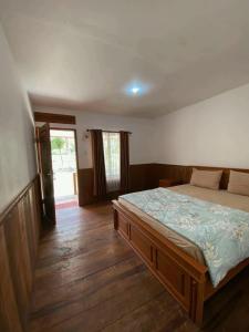 a bedroom with a bed and a wooden floor at Katra Sembalun in Sembalun Lawang