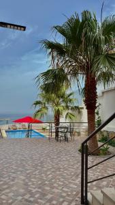 a patio with tables and palm trees next to a pool at zahara appartement in Tangier
