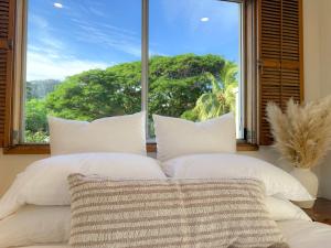 a bed with white pillows in front of a window at The Balcony at Airlie in Airlie Beach
