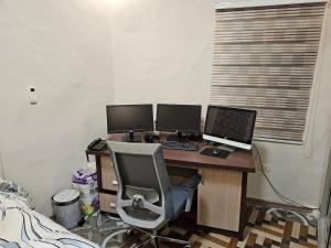 a computer desk with two monitors and a laptop at A nice one bedroom apartment in Mills Center