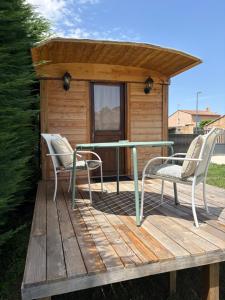 a deck with two chairs and a table and a cabin at Chicken roulotte des 3 cèdres in Cavaillon