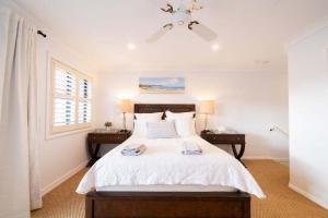a bedroom with a white bed with two night stands at Avoca Beachside Retreat in Avoca Beach