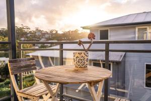 a wooden table with a flower in a vase on a balcony at Avoca Beachside Retreat in Avoca Beach