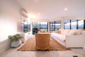 a living room with a white couch and some windows at Avoca Beachside Retreat in Avoca Beach