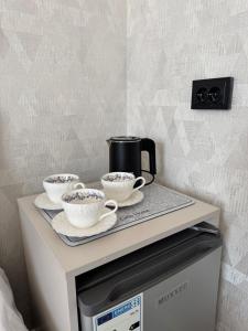 a tray with three cups of coffee on top of a microwave at Zere Motel in Türkistan