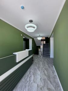 a hallway with green walls and a ceiling with a staircase at Zere Motel in Türkistan