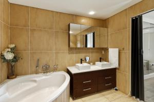 a bathroom with a tub and a sink and a mirror at Luxury Ocean View 1203 with Workspace, AC & Beachfront Location in Cape Town