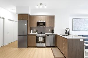 a kitchen with wooden cabinets and stainless steel appliances at Stylish Skyview Condo in Kitchener Downtown in Kitchener