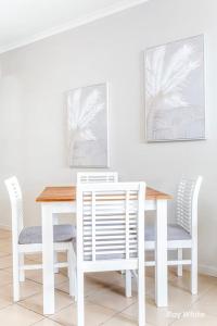 a white dining room table and chairs with paintings on the wall at Sea Air 6 in Yeppoon +1 photo