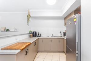 a kitchen with white cabinets and a stainless steel refrigerator at Sea Air 6 in Yeppoon