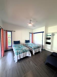 a bedroom with two beds and a ceiling fan at Kuki Kainga in Matavera