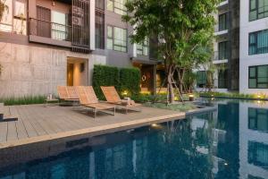 a swimming pool with two chairs next to a building at BTS Thong Lor Central High -rise Condo in Bangkok