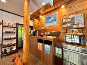 a kitchen with wooden walls and a counter with a stove at Pension Kobekko in Otari