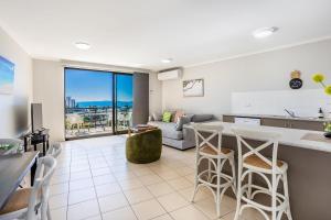 a kitchen and living room with a counter and stools at Sea Air 24 in Yeppoon