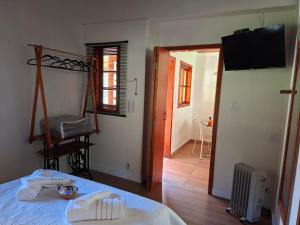 ein Zimmer mit einem Bett und ein Flur mit einem Fernseher in der Unterkunft Chalé Cabana Ruby in Gonçalves