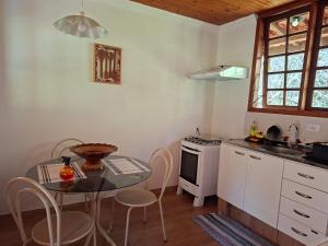 eine Küche mit einem Tisch und einem kleinen Tisch mit Stühlen in der Unterkunft Chalé Cabana Ruby in Gonçalves