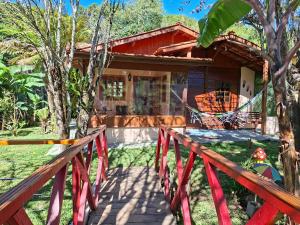 ein Haus mit einer roten Brücke davor in der Unterkunft Chalé Cabana Ruby in Gonçalves