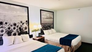 a hotel room with two beds and a painting on the wall at Four Seasons Inn in Bottineau