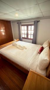 a large bed in a room with a window at Traditional Thai House Chaloklum in Chaloklum
