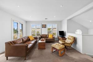 a living room with leather couches and chairs at Willos in Queenscliff