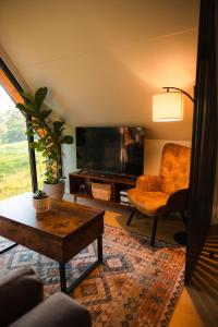 a living room with a tv and a chair and a table at Bison Farm - Cabin "Cielo" in Culpeper