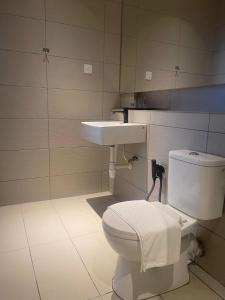 a bathroom with a white toilet and a sink at Roxy Hotel Selangau in Rumah Kudan