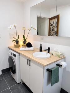 a bathroom with a sink and a washing machine at William's on William - Stylish 2 Bedroom Haven in Ormiston
