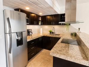 a kitchen with a stainless steel refrigerator and wooden cabinets at Beachfront condo with loft and sea views in Puerto Aventuras