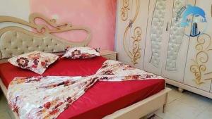 a bed with a red comforter and pillows on it at Résidence Marina in Sousse