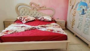 a bed with a red comforter and two pillows at Résidence Marina in Sousse