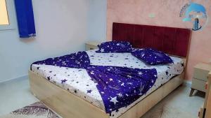 a bedroom with a bed with purple sheets and pillows at Résidence Marina in Sousse +3 photos