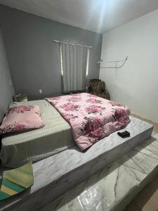 a bedroom with a bed with a pink comforter at Casa com piscina in Belfort Roxo
