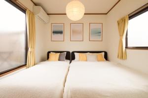 two beds in a room with two windows at Matsumoto BASE in Matsumoto