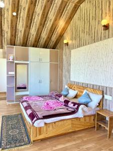 a bedroom with a bed and a wooden wall at Orchard Valley Resort in Mai Jūbar