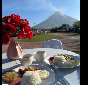 a table with two plates of food and a vase with roses at Ondue Hotel & Events Place in Camalig